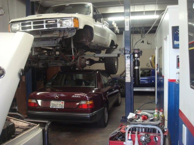 An auto mechanic's car on a lift in a garage.