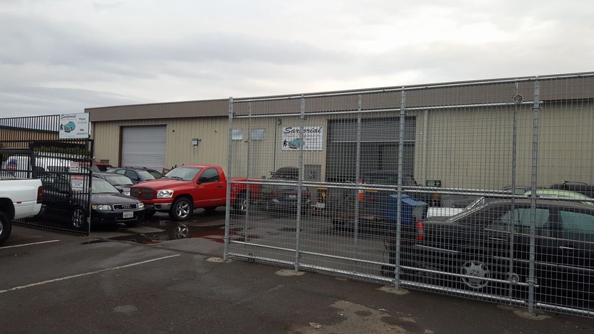 A mechanic's building with several cars parked in front of it.