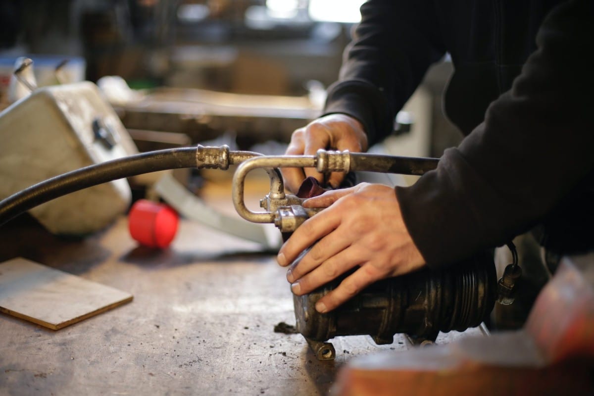 A car mechanic is working on a hose in a workshop.