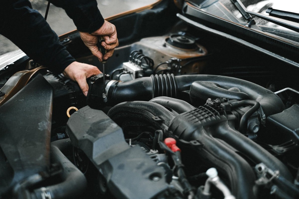 An auto mechanic is working on the engine of a car.