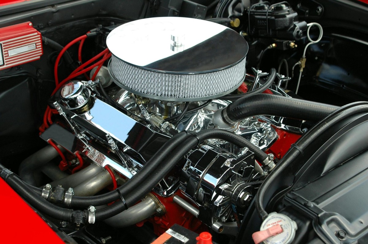 Detailed view of a polished car engine featuring chrome parts, hoses, and a large air filter in a vehicle with a red interior.