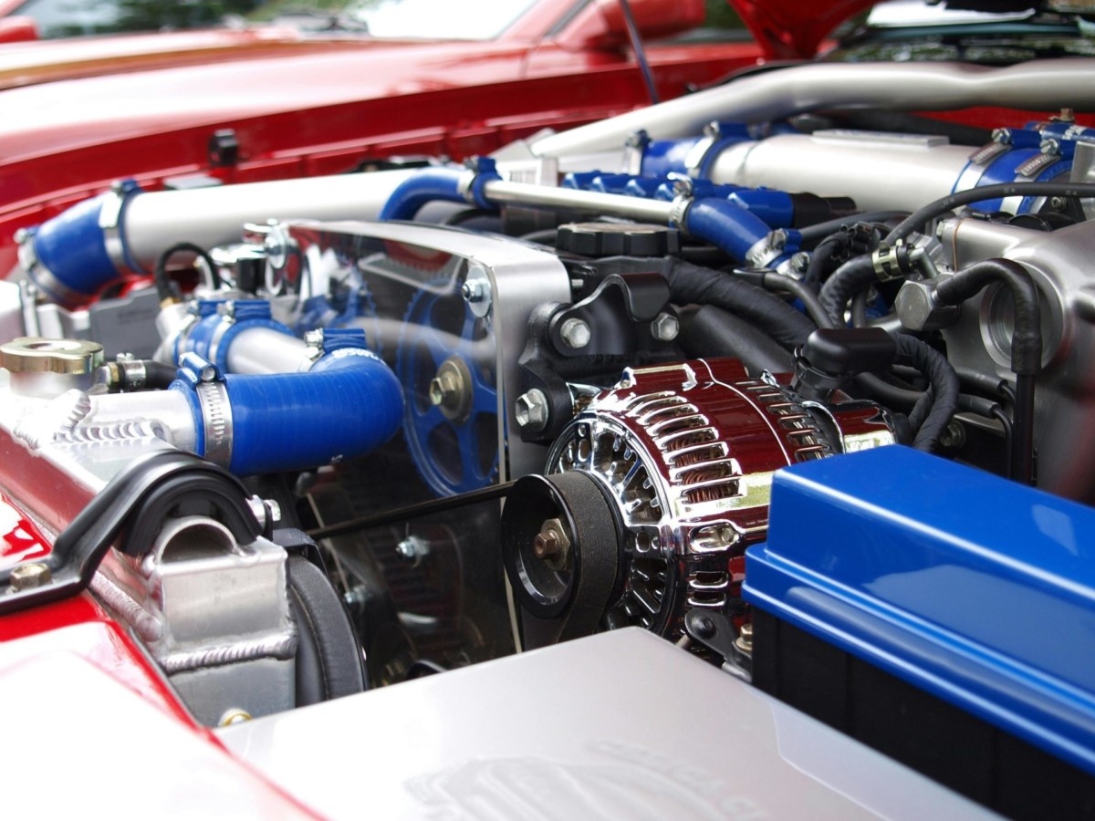 Close-up of a car engine with visible components and blue silicone hoses, highlighting the detailed setup and shiny chrome parts.