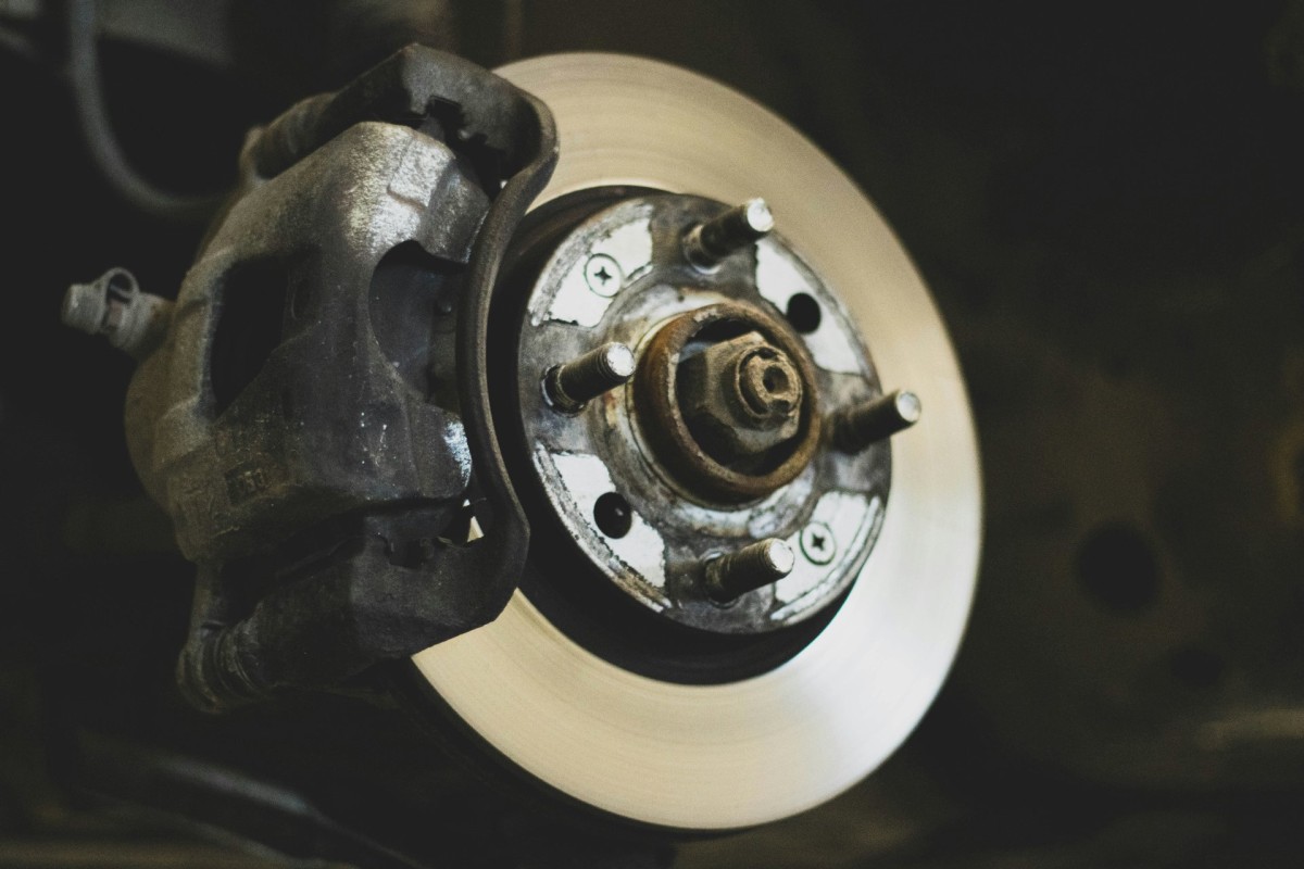 Close-up view of a car wheel hub and brake rotor with the caliper attached, highlighting mechanical components and metal surfaces—an essential focus for anyone concerned about brake repair or the risks of delaying brake repair.